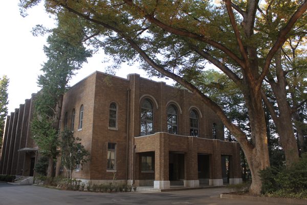 The brick lecture hall under large trees at Musashi University, Ekoda